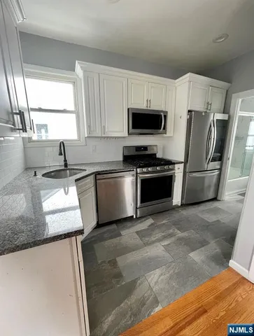 a kitchen with stainless steel appliances granite countertop a sink a stove a microwave a refrigerator a counter space and cabinets