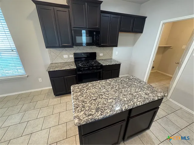 a kitchen with stainless steel appliances granite countertop a stove a sink and a microwave