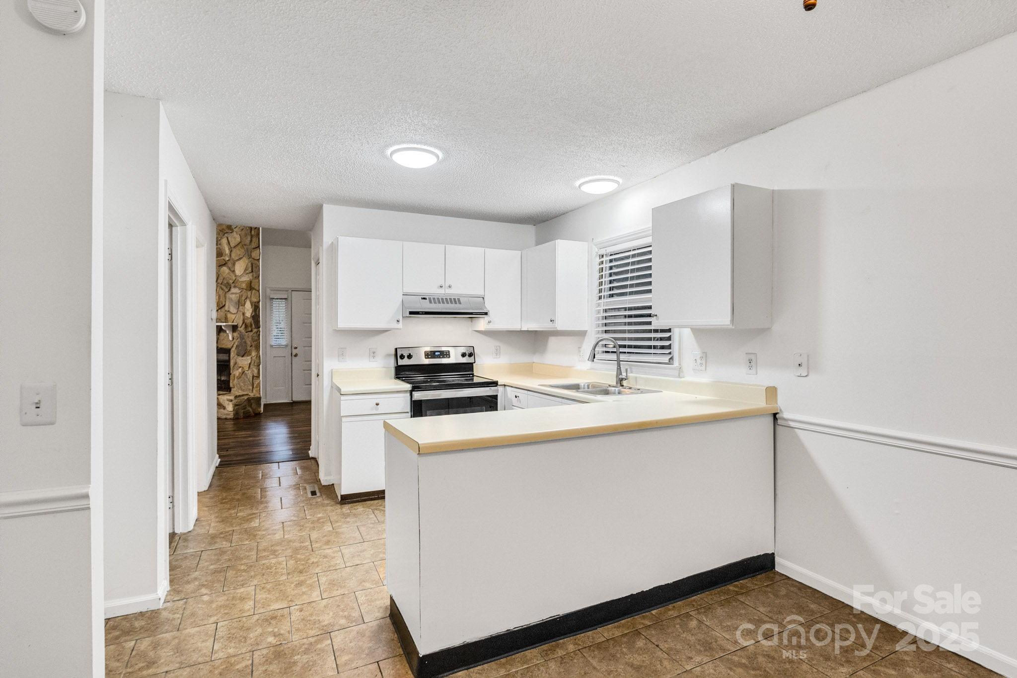 27097 Cove Lane Tega Cay, SC 29708 - Photo 25 of 30 a kitchen with kitchen island white cabinets and white appliances