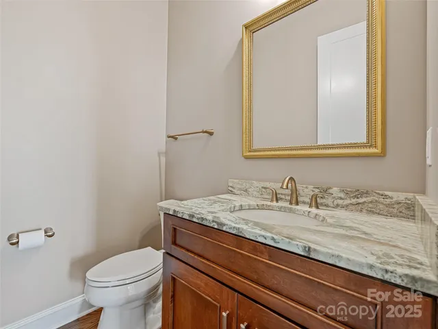 a bathroom with a granite countertop sink a toilet and mirror