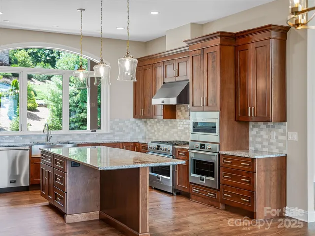 a kitchen with stainless steel appliances granite countertop a stove a sink and a refrigerator