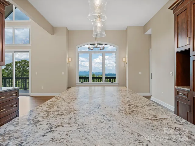 a view of an empty room with a window and kitchen view