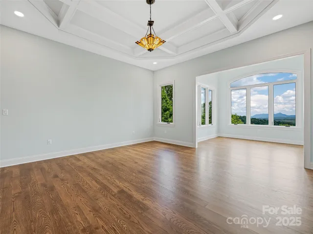 a view of an empty room with window and wooden floor