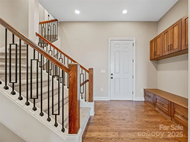 a view of staircase with lots of frames on wall and wooden floor