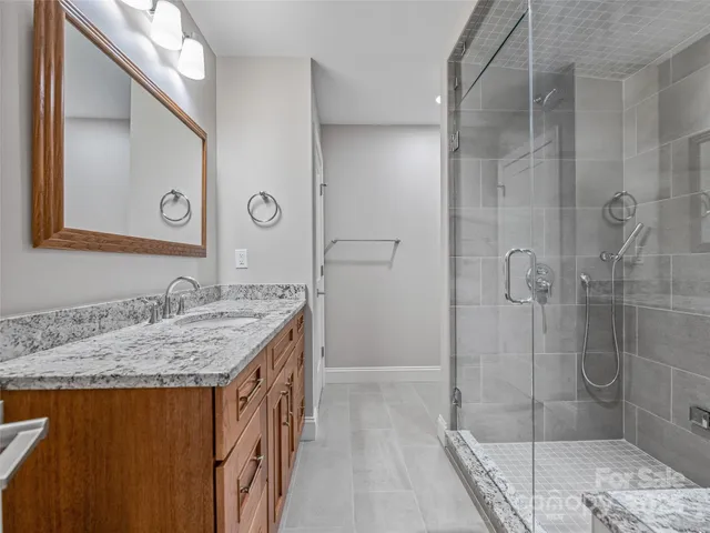 a bathroom with a granite countertop sink a mirror and shower