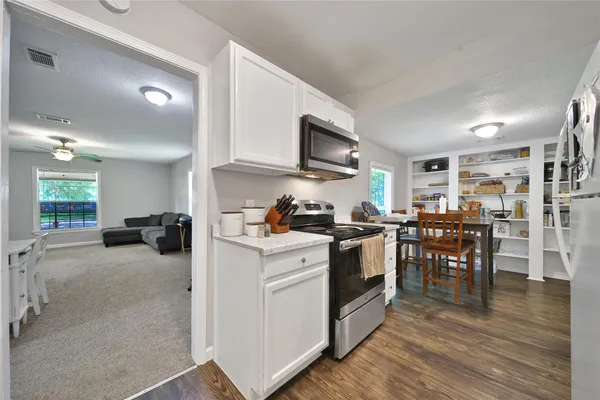 a kitchen with stainless steel appliances a stove a sink a oven a dining table and chairs
