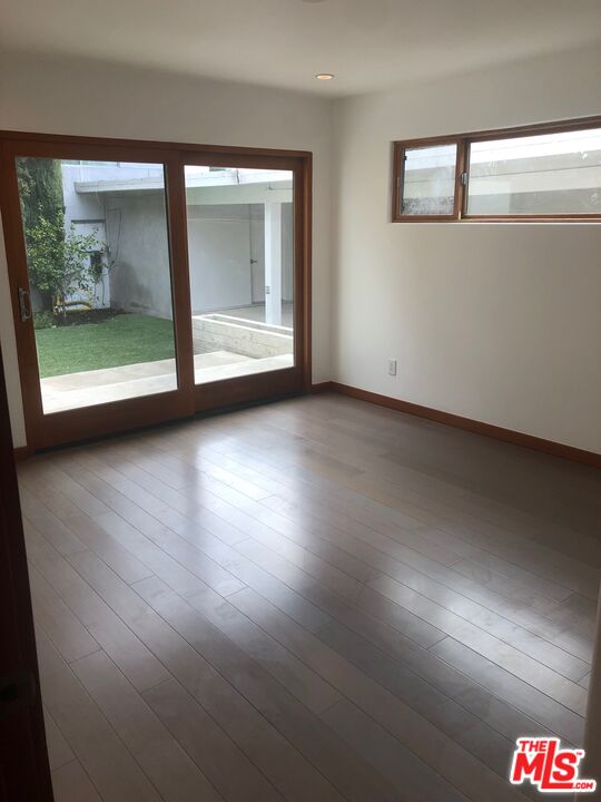 128 South Carson Road Beverly Hills, CA 90211 - Photo 12 of 20 an empty room with wooden floor and windows