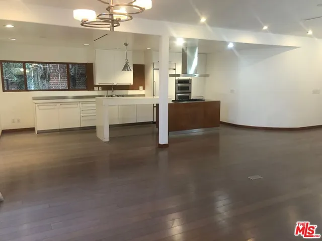 a large white kitchen with a sink and dishwasher a stove top oven with wooden floor