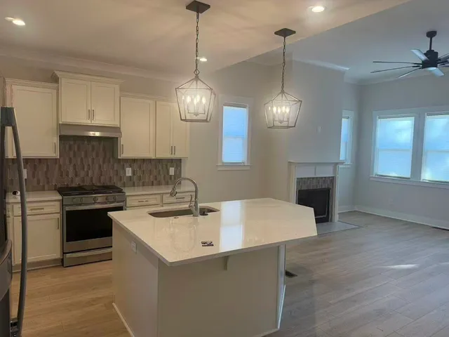 a kitchen with stainless steel appliances granite countertop a sink a stove and a wooden floors