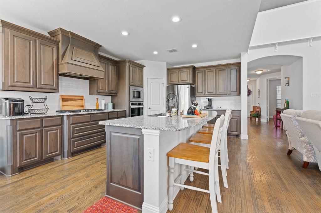 15105 Fleet Hill Road Aledo, TX 76008 - Photo 10 of 31 a kitchen with stainless steel appliances kitchen island granite countertop a stove a sink a refrigerator and white cabinets with wooden floor