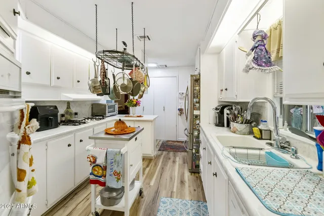a kitchen with stainless steel appliances granite countertop a sink a stove a refrigerator and a wooden floor