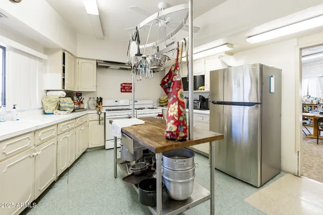 a kitchen with stainless steel appliances kitchen island granite countertop a refrigerator a sink dishwasher and white cabinets with wooden floor