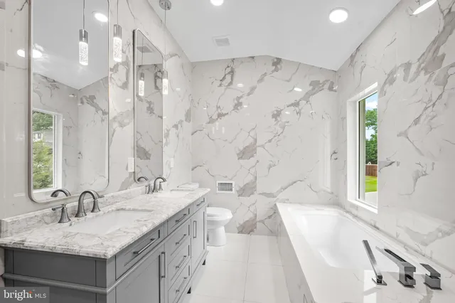 a bathroom with a granite countertop sink a mirror a bathtub and shower