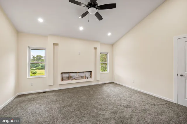 an empty room with windows and ceiling fan