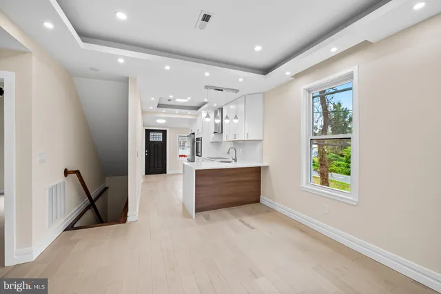 a large white kitchen with kitchen island a large window a sink and a stove top oven