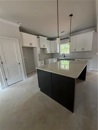 a kitchen with kitchen island granite countertop a sink a counter space and cabinets