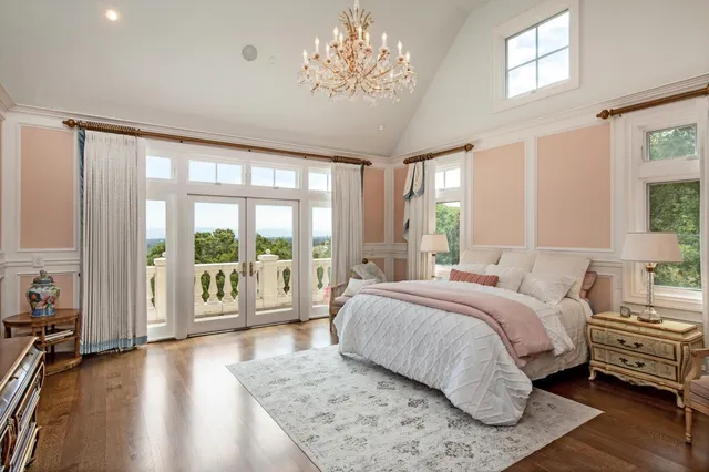 a spacious bedroom with a large bed and a chandelier next to a large window