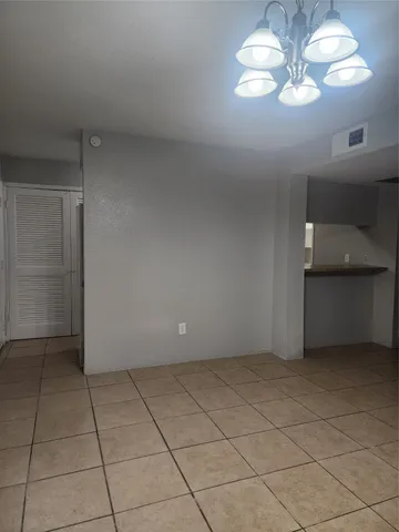 a view of an empty room with a chandelier fan