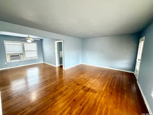 an empty room with wooden floor and windows