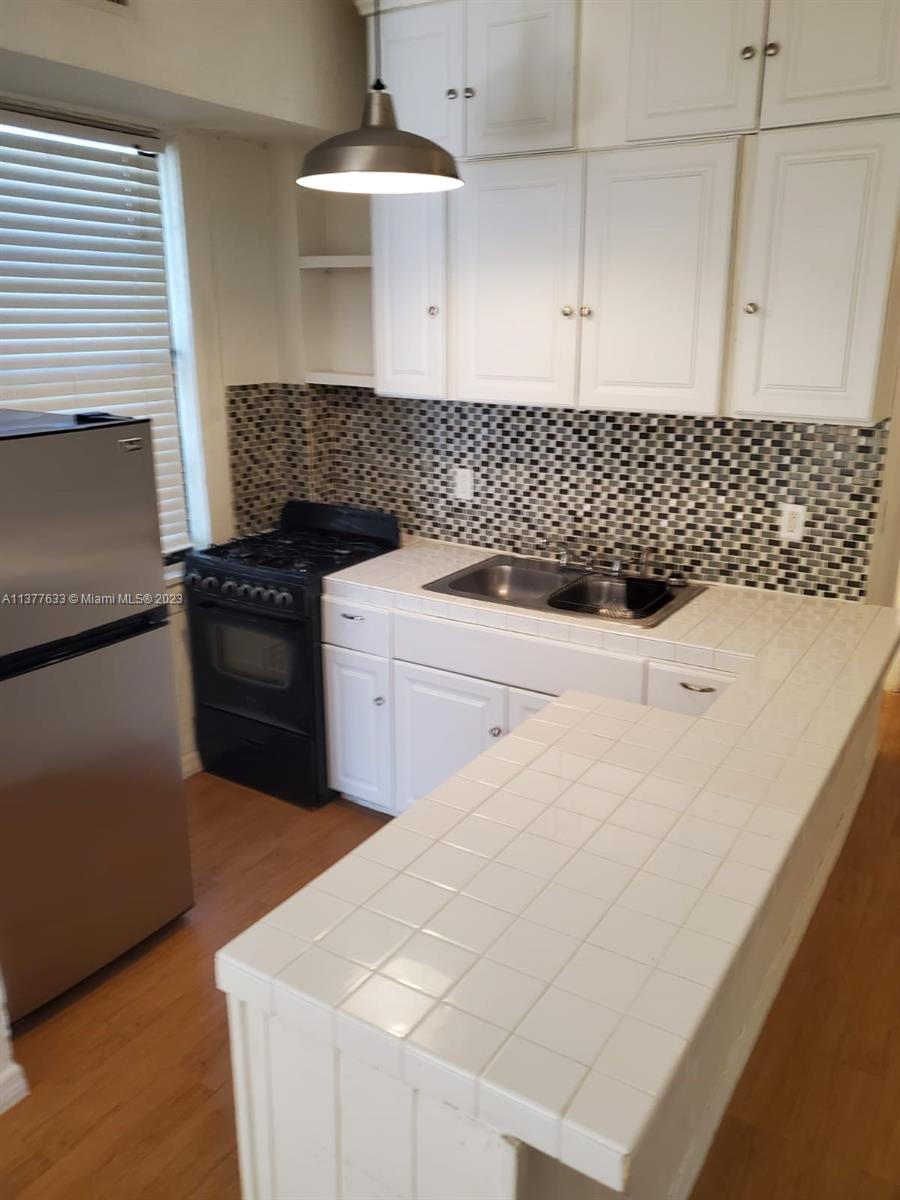 a kitchen with granite countertop a sink a stove and cabinets