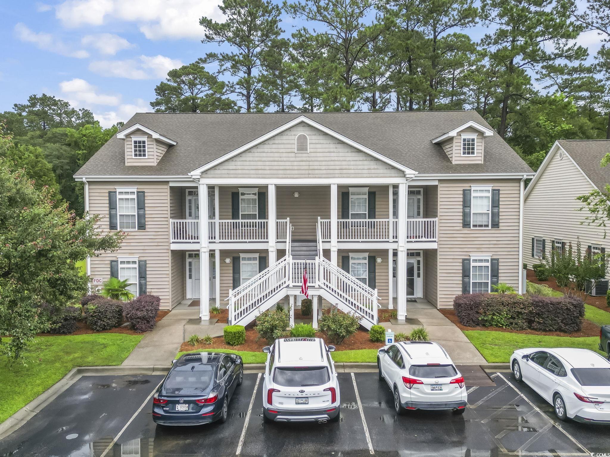 View of front of property with a shingled roof, uncovered parking, stairway, and a porch