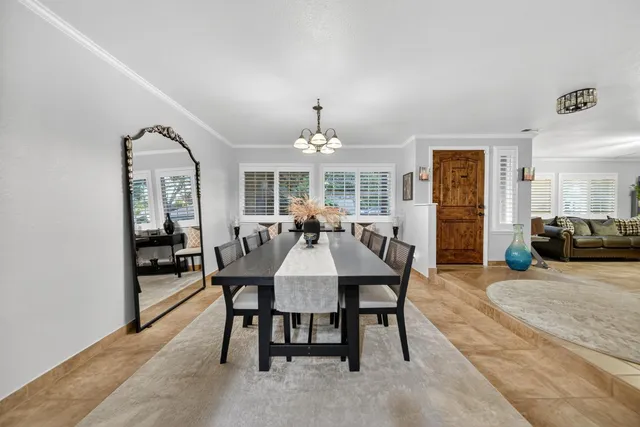 a dining room with wooden floor a chandelier a wooden table and chairs
