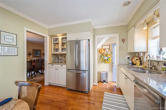 a kitchen with granite countertop stainless steel appliances a refrigerator cabinets and wooden floor