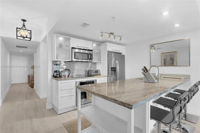 a kitchen with kitchen island granite countertop a stove a sink a refrigerator dining table and chairs