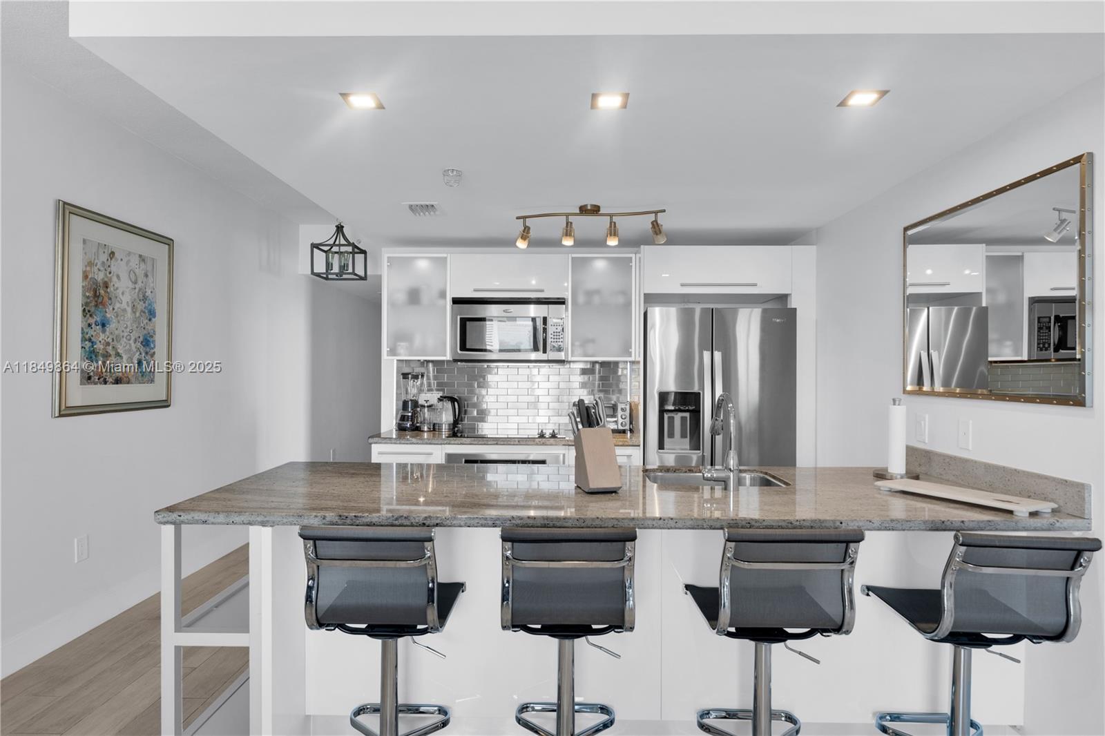 185 Southwest 7th Street, Unit 1901 Miami, FL 33130 - Photo 6 of 46 a kitchen with stainless steel appliances kitchen island granite countertop a dining table chairs and a refrigerator