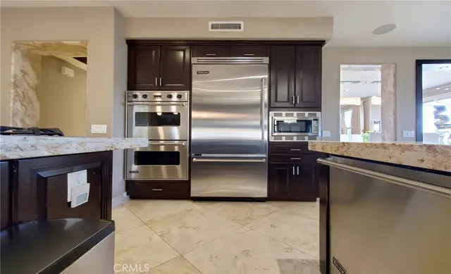 a large kitchen with stainless steel appliances kitchen island granite countertop a table chairs in it and a window