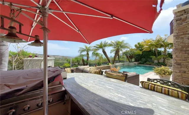 a view of a patio with couches table and chairs under an umbrella with a fire pit and a yard