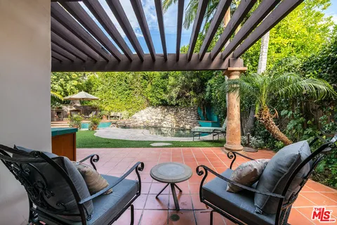 a view of pool with lawn chairs under an umbrella