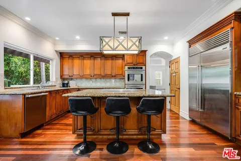 a kitchen with stainless steel appliances granite countertop a refrigerator a stove a sink and dishwasher with wooden floor