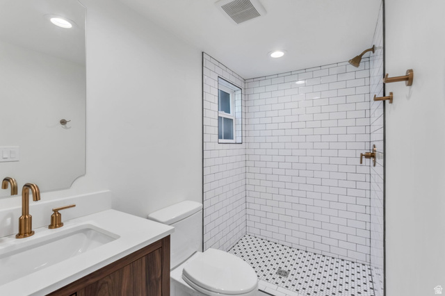 226 North 300 West Provo, UT 84601 - Photo 14 of 14 Bathroom featuring a wood-finish vanity with an integrated sink and white countertop, bronze-tone fixtures, a tiled shower with a clear glass enclosure, and recessed lighting