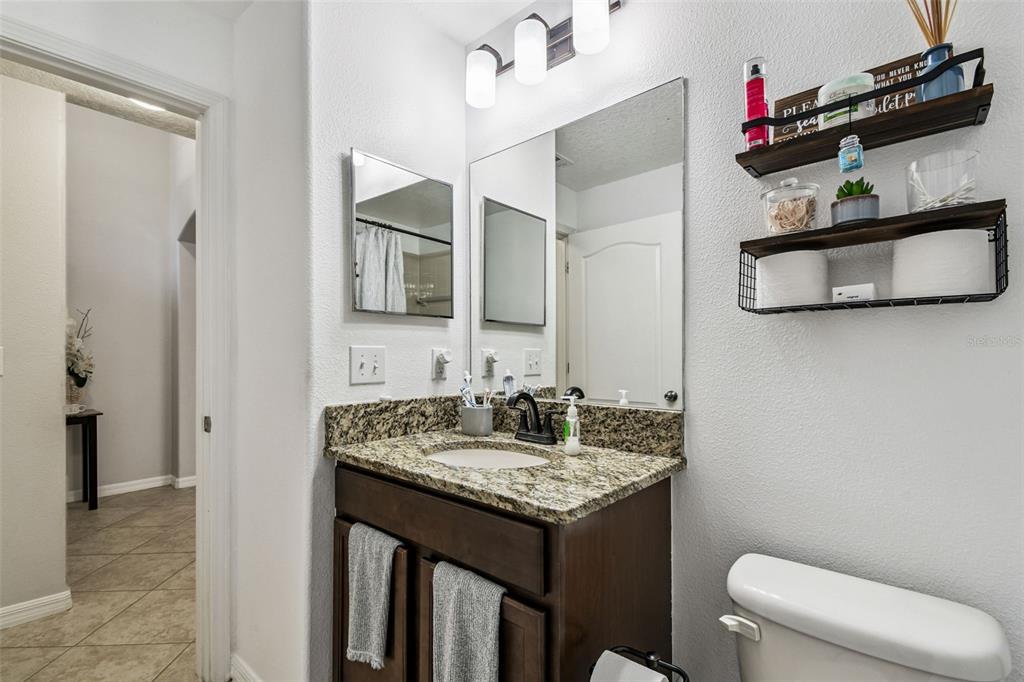 8439 Hunters Fork Loop Ruskin, FL 33573 - Photo 11 of 74 a bathroom with a granite countertop sink a toilet and a mirror