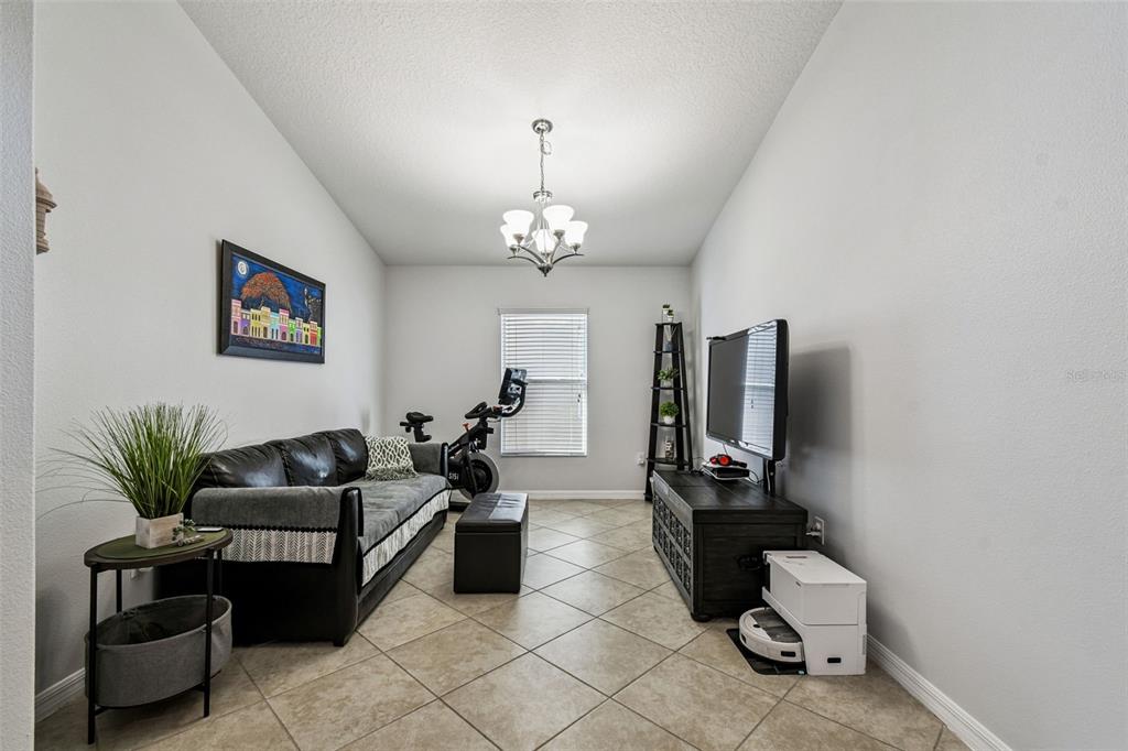 8439 Hunters Fork Loop Ruskin, FL 33573 - Photo 15 of 74 a living room with furniture a flat screen tv and gym equipment