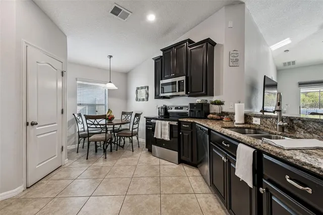 a kitchen with stainless steel appliances kitchen island granite countertop a stove a sink a dining table and chairs