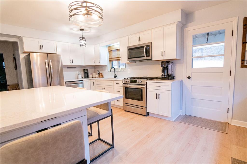 1005 Paintertown Road Irwin, PA 15642 - Photo 5 of 33 a kitchen with stainless steel appliances a stove a sink dishwasher a refrigerator white cabinets and wooden floor