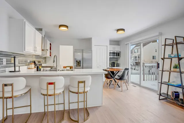 a kitchen with stainless steel appliances granite countertop a table and chairs in it