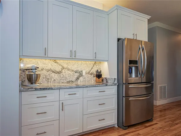 a kitchen with granite countertop white cabinets and stainless steel appliances