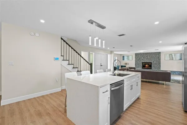 a large white kitchen with a sink and dishwasher a stove with wooden floor
