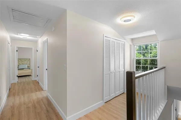 a view of a hallway with wooden floor and a bathroom