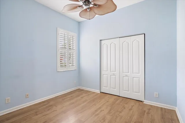 an empty room with a chandelier fan and wooden floor