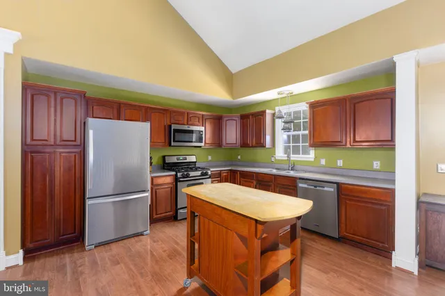 a kitchen with stainless steel appliances granite countertop a refrigerator a sink dishwasher a stove with wooden cabinets and floor