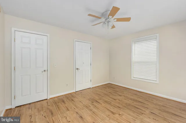 an empty room with wooden floor closet and windows