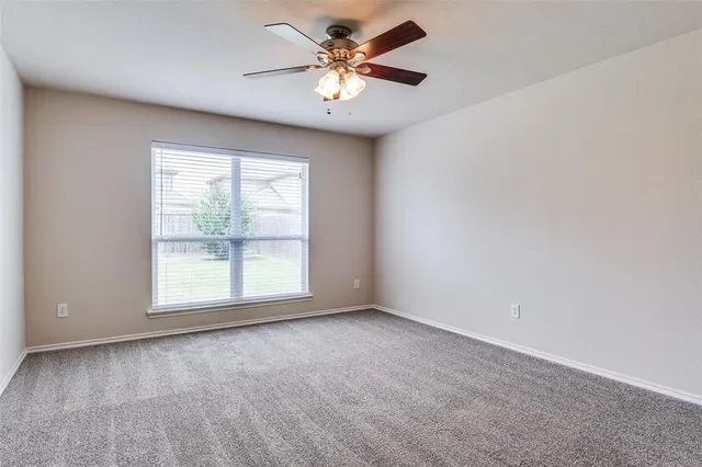 an empty room with windows and ceiling fan