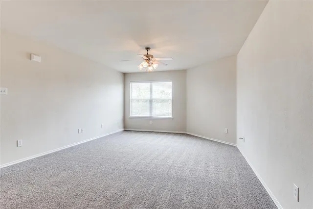 an empty room with windows and chandelier fan