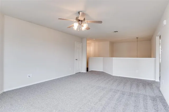 an empty room with chandelier fan and windows