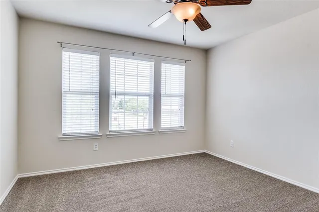 an empty room with a window and a ceiling fan