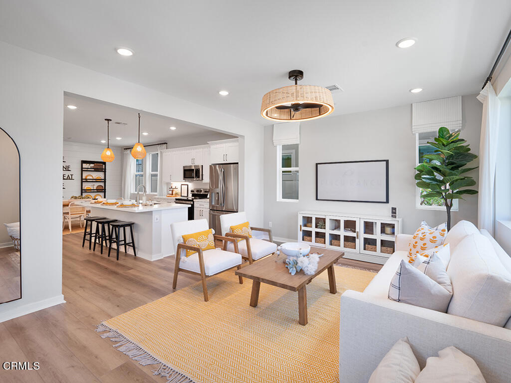 a living room with furniture kitchen view and a wooden floor